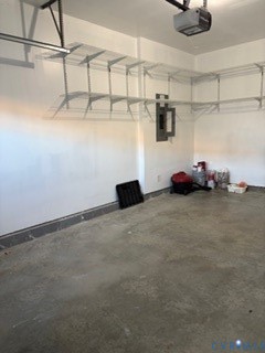 Garage interior featuring concrete flooring, white-painted walls, mounted wire shelving, and an integrated garage door opener