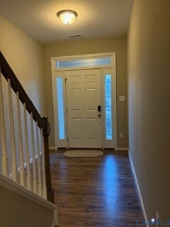 Entryway featuring a white panel door with sidelights and transom window, wood-finish flooring, and a staircase with a wooden handrail and white balusters