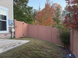 Backyard featuring a concrete patio, solid vinyl privacy fencing, and stone veneer foundation detailing