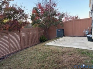 Rear outdoor space featuring a concrete patio, horizontal-slat privacy fencing, and mature trees