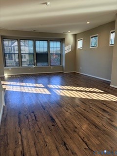 Spacious room featuring wood-finish flooring, a large bay window, recessed ceiling lighting, and multiple square-pane windows