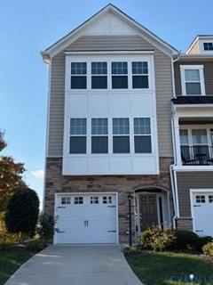 Multi-story exterior featuring stone veneer siding, horizontal siding, a bay window with grid-pane glass, and an attached single-car garage with hardware accents