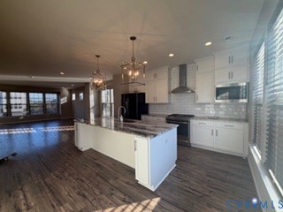 Kitchen featuring white cabinetry, stone-surface island, wood-finish flooring, subway tile backsplash, and stainless steel appliances
