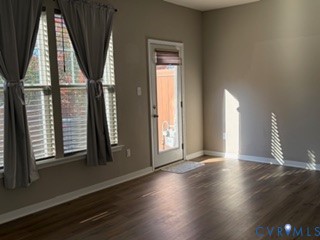 Interior space featuring wood-finish flooring, neutral wall paint, and dual windows with window blinds