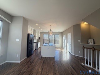 Kitchen featuring an island with a stone countertop, wood-finish flooring, white cabinetry, recessed lighting, and a pendant fixture