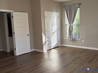 Room featuring wood-finish flooring, white paneled doors, and a double-door closet with metallic hardware
