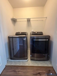 Laundry alcove featuring dark metallic-finish appliances, a protective floor drip tray, and a white wire-grid overhead storage shelf