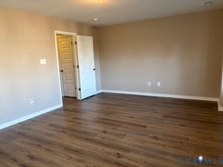 Room featuring wood-finish flooring, neutral-toned walls, and a five-panel interior door