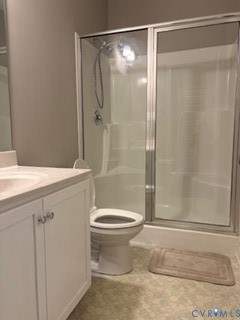 Bathroom featuring a white vanity cabinet with an integrated sink, polished chrome hardware, a walk-in shower with a glass enclosure, and a handheld showerhead fixture