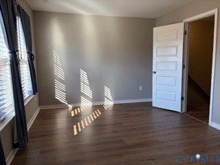 Room featuring wood-finish flooring, neutral wall paint, and a five-panel interior door