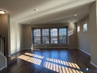 Open-concept space featuring wood-finish flooring, recessed lighting, and a prominent bank of multi-pane windows