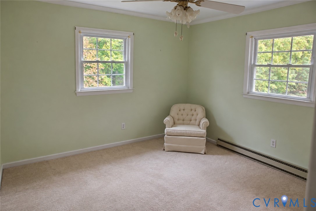 Room featuring wall-to-wall carpeting, two double-hung windows with exterior greenery, and a ceiling-mounted light fixture with fan Room featuring wall-to-wall carpeting, two double-hung windows with exterior greenery, and a ceiling-mounted light fixture with fan