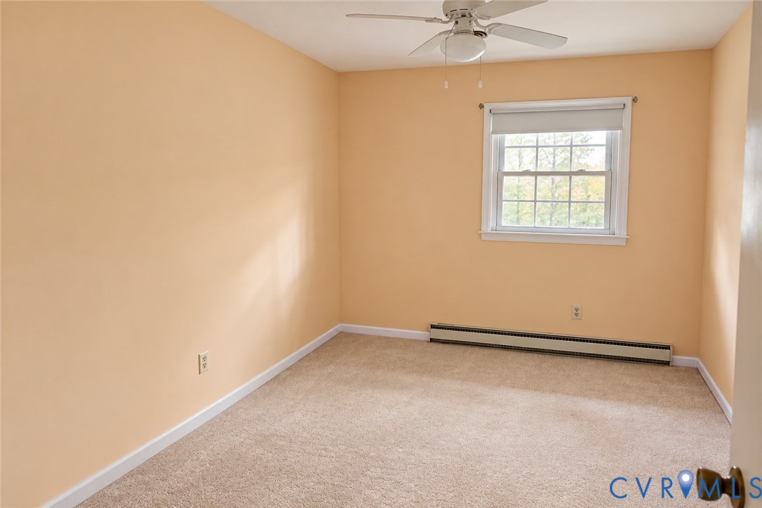 Room featuring neutral wall tones, wall-to-wall carpeting, a multi-pane window with a roller shade, and a ceiling-mounted fan with light fixture Room featuring neutral wall tones, wall-to-wall carpeting, a multi-pane window with a roller shade, and a ceiling-mounted fan with light fixture