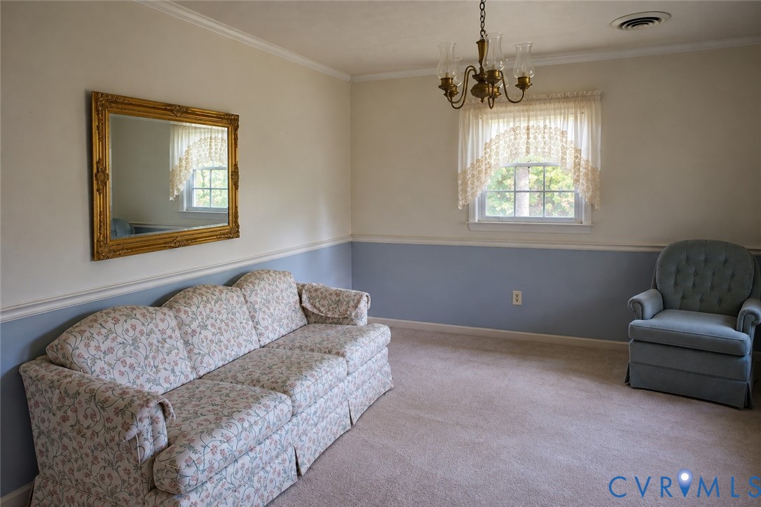 Multi-toned wall paint separated by chair rail molding, carpeted flooring, multi-pane window with valance, and a multi-arm metallic chandelier Multi-toned wall paint separated by chair rail molding, carpeted flooring, multi-pane window with valance, and a multi-arm metallic chandelier