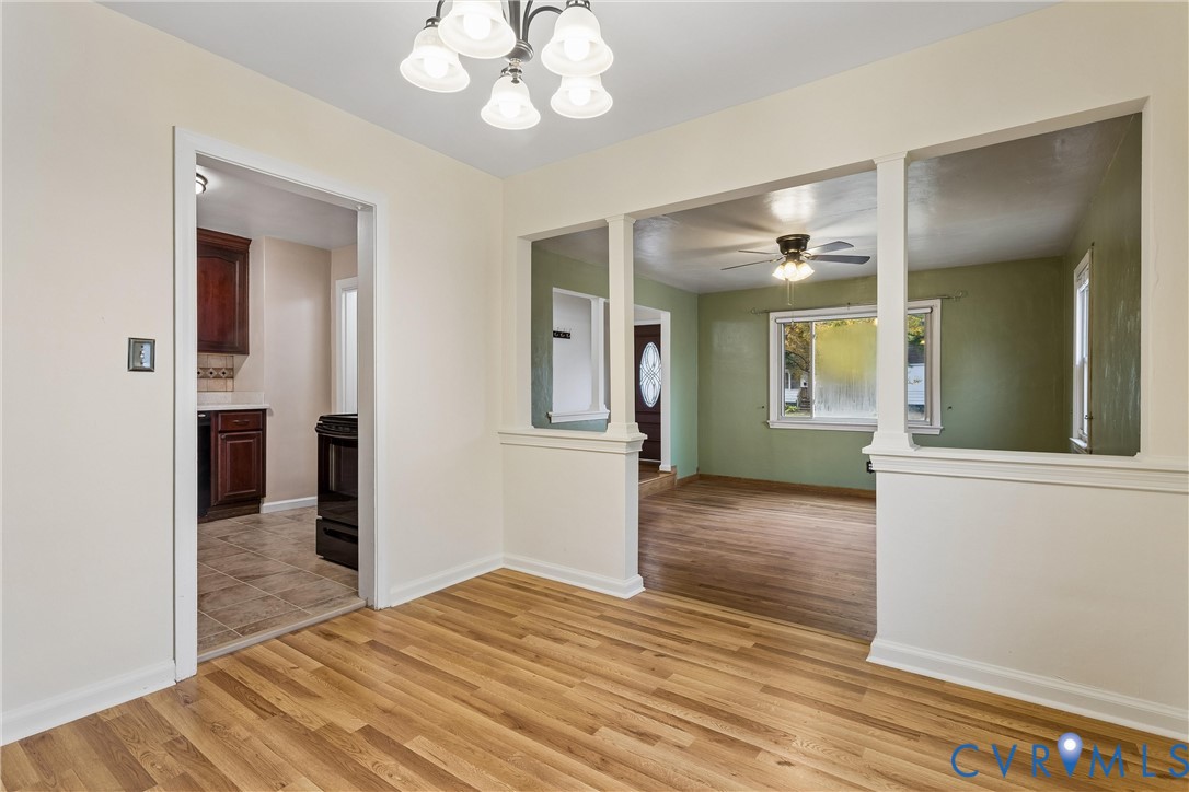 Dining area featuring wood-finish flooring, a multi-light chandelier, and decorative wall cutouts with chair rail molding
