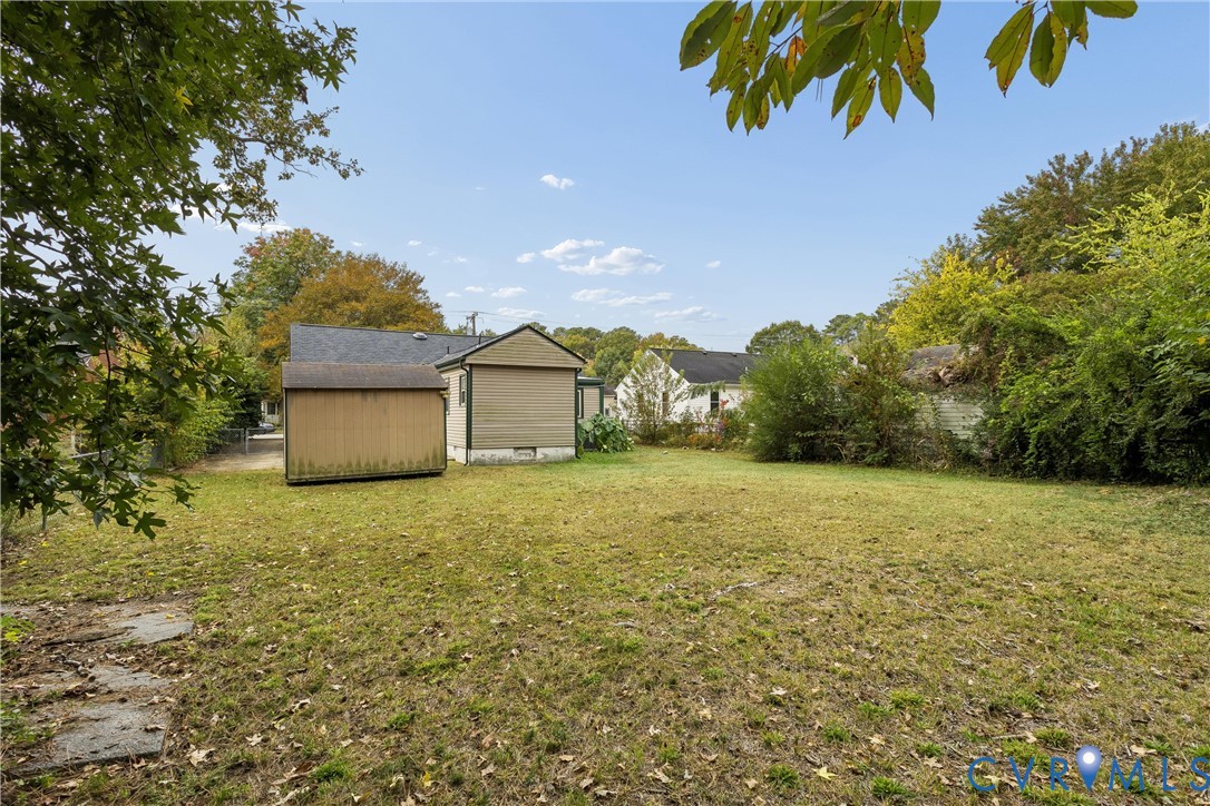 Expansive backyard featuring a level lawn, mature trees, and a detached storage structure