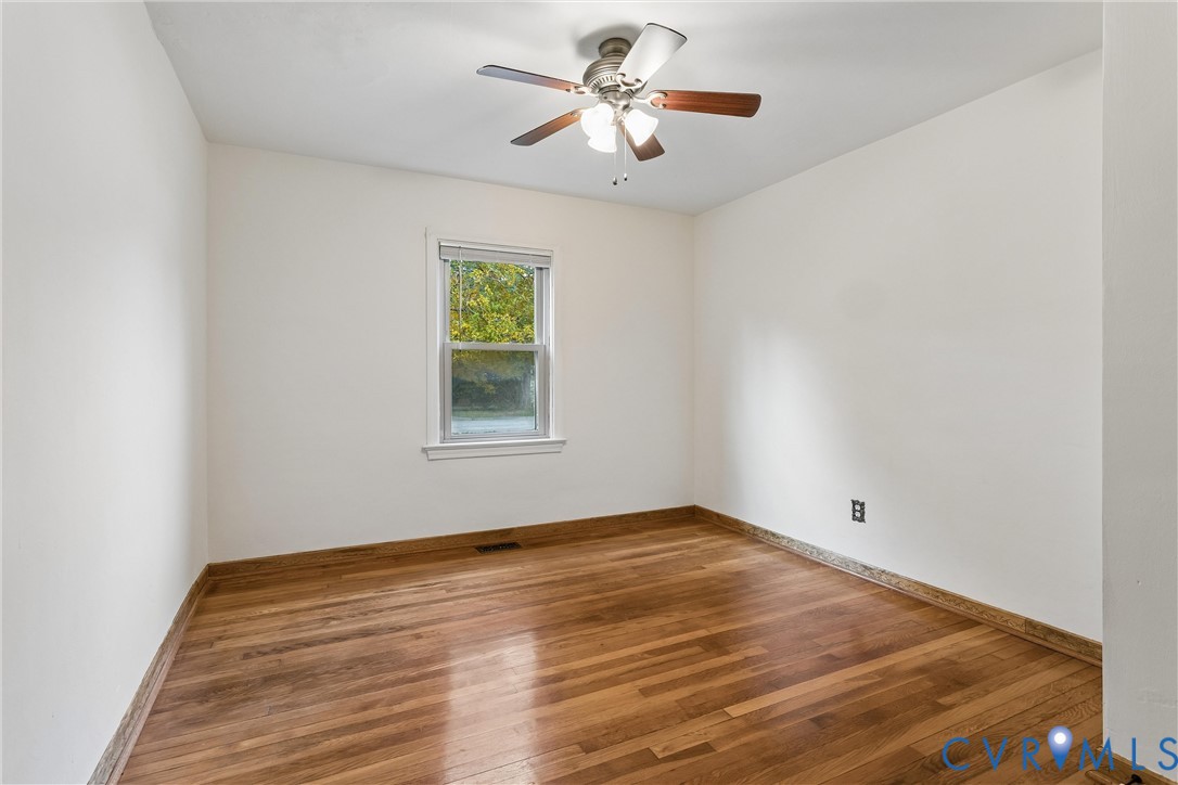 Room featuring wood-finish flooring, a central ceiling fan with integrated light fixture, and a single-pane window