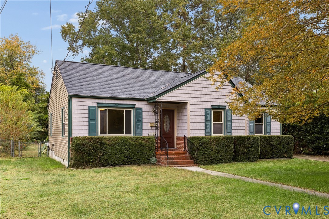 Exterior featuring light-toned shingle siding, brick-tread front steps, decorative window shutters, an arched-glass entry door, and a gabled roofline