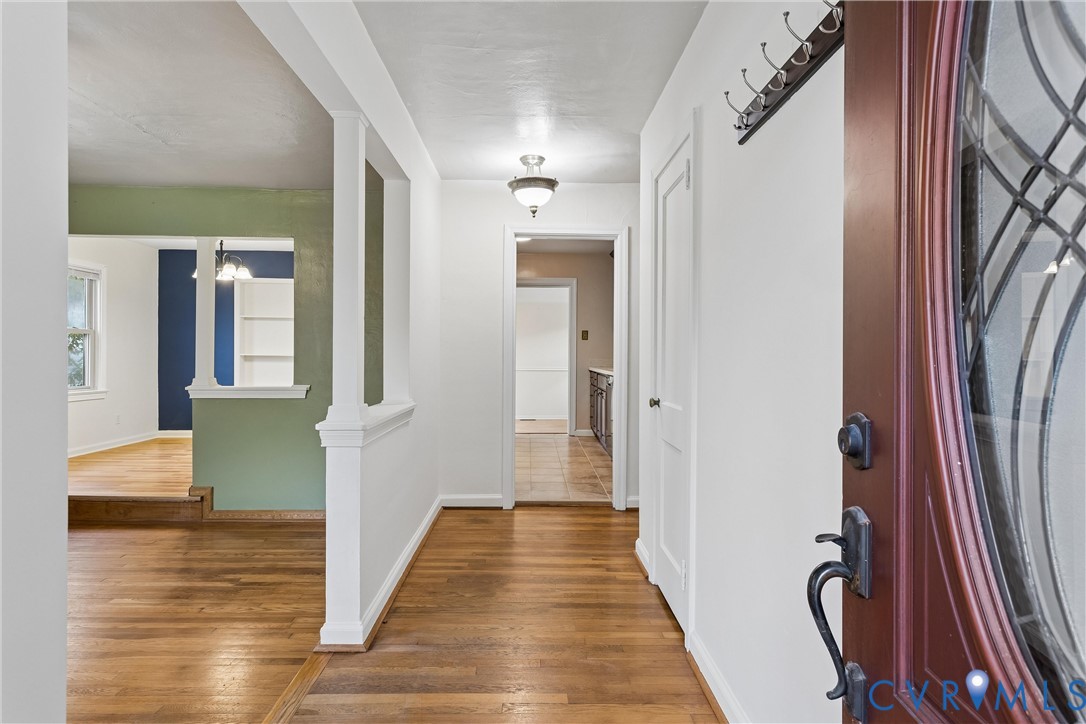 Entryway featuring wood-finish flooring, half-wall room divider with a decorative column, recessed lighting, and a multi-pane glass insert door with dark finish hardware