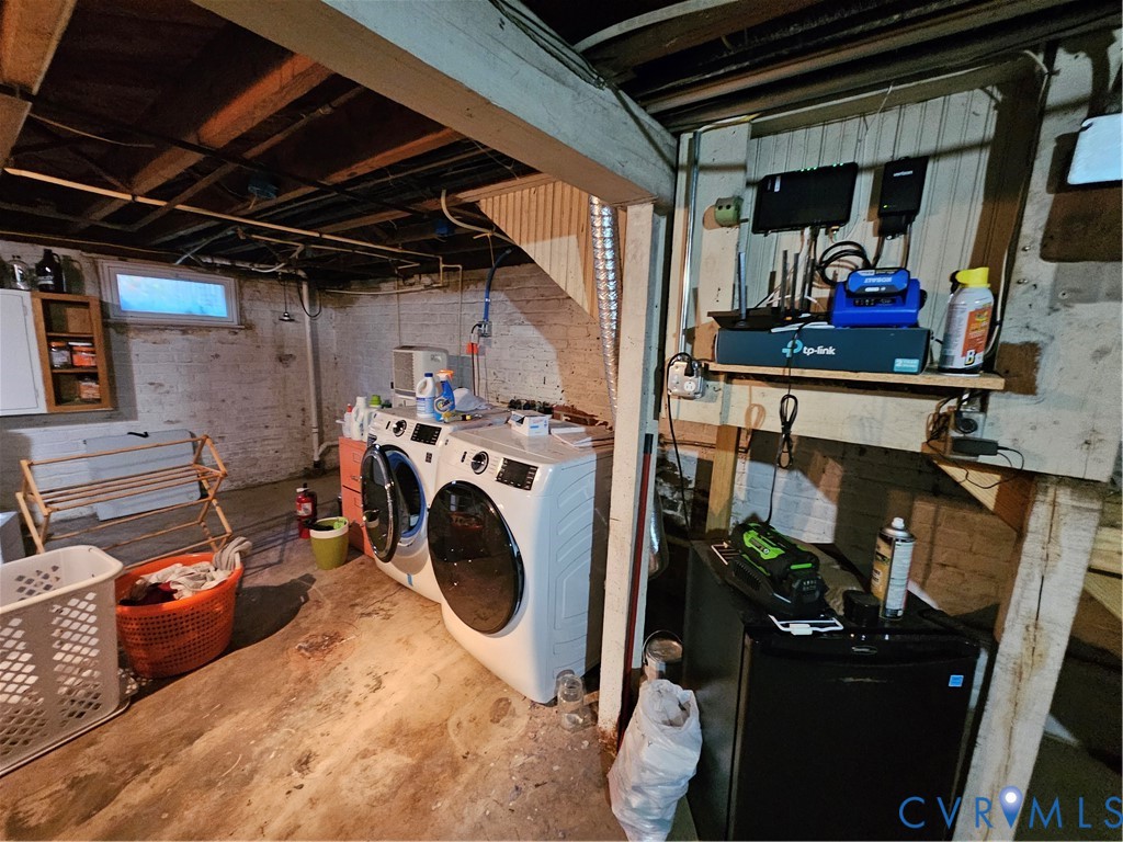 Unfinished utility area featuring exposed joist ceiling, painted masonry walls, and integrated laundry hookups