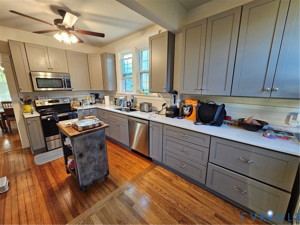 Kitchen featuring shaker-style grey cabinetry, white countertops, stainless steel appliances, and wood-finish flooring