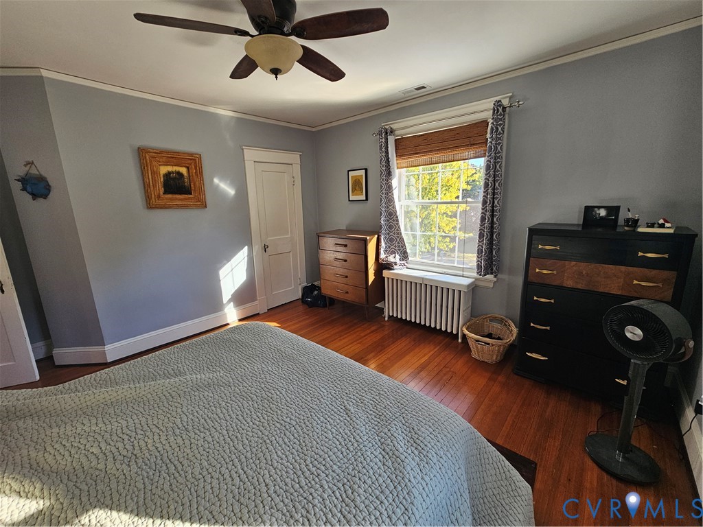 Hardwood flooring, multi-pane window, ceiling fan with integrated lighting, and crown molding