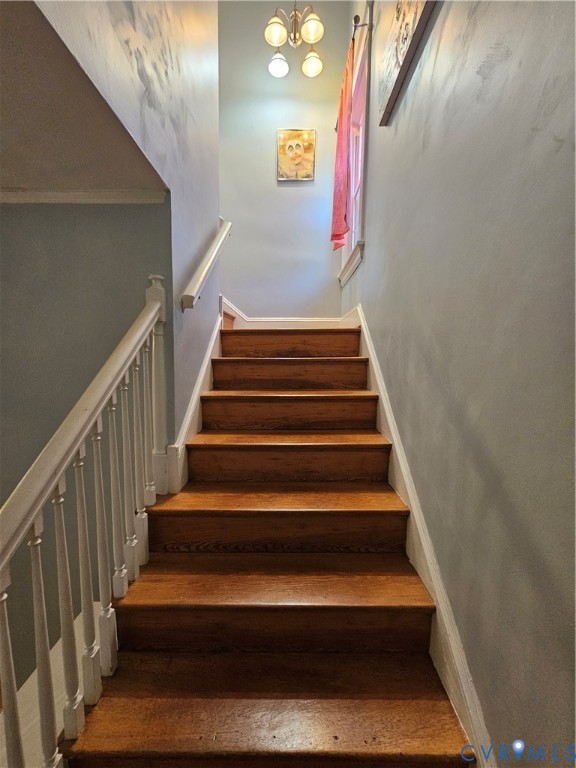 Staircase featuring wood-finish treads, white painted spindles, a matching handrail, and a four-light fixture