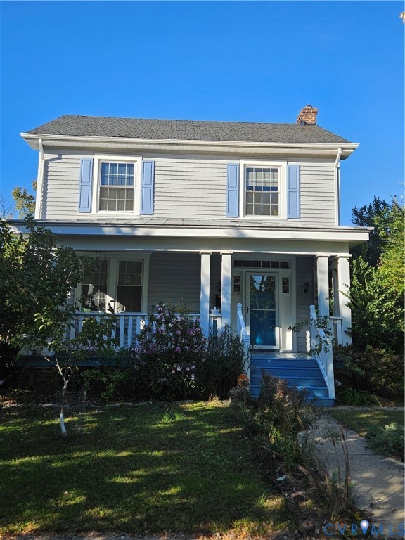 Two-story residence featuring light gray horizontal siding, decorative blue shutters, a covered front porch with square columns, and a front entry door with transom and side lights