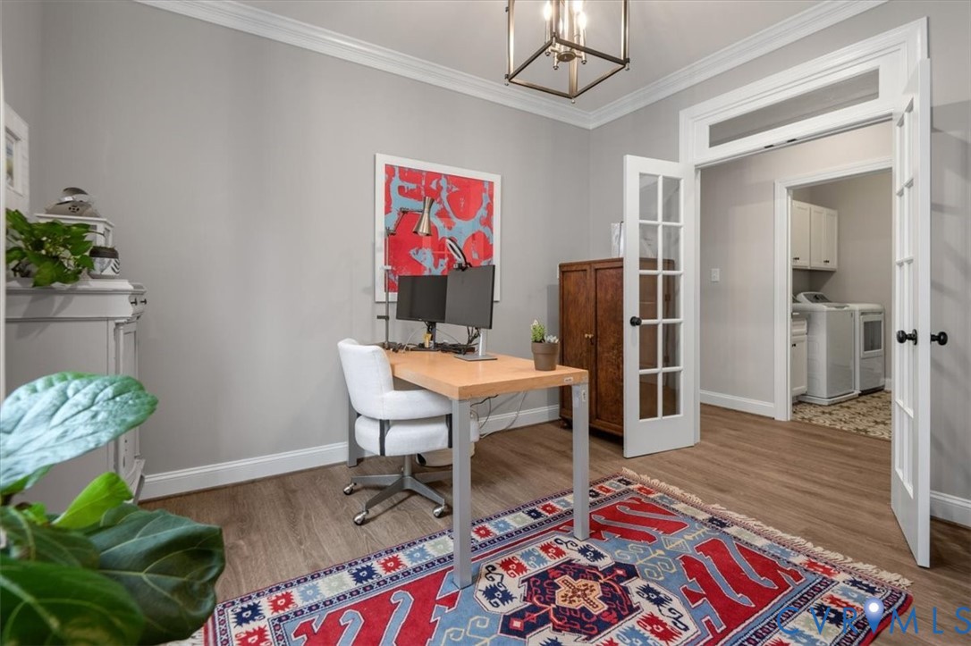 Room featuring wood-finish flooring, crown molding, a geometric metal-frame chandelier, and French doors with glass panes and transom windows