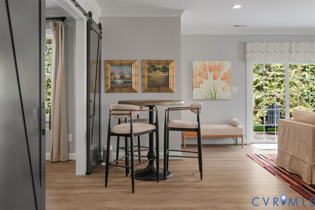 Terrace Level -Sliding barn-style door, wood-finish flooring, crown molding, and glass sliding door featuring natural light