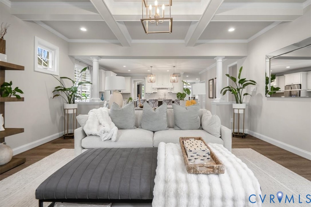 Coffered ceiling with crown molding, wood-finish flooring, architectural columns, geometric metal pendant lighting, and recessed ceiling lights