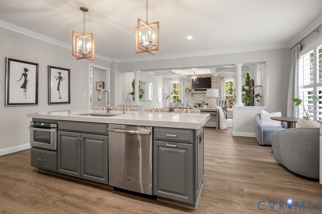 Kitchen island featuring grey cabinetry, stone-finish countertops, stainless steel appliances, and dual geometric pendant lighting over wood-finish flooring