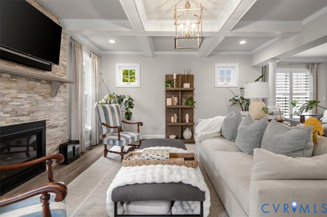 Coffered ceiling featuring recessed lighting and a central lantern-style pendant, stacked-stone fireplace surround, wood-finish flooring, and built-in shelving