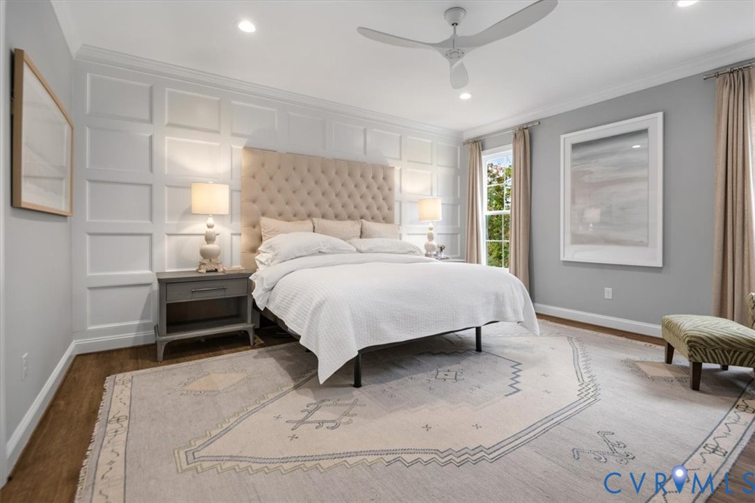 Interior room featuring white wainscoting accent wall, wood-finish flooring, recessed lighting, and a modern white ceiling fan with integrated light