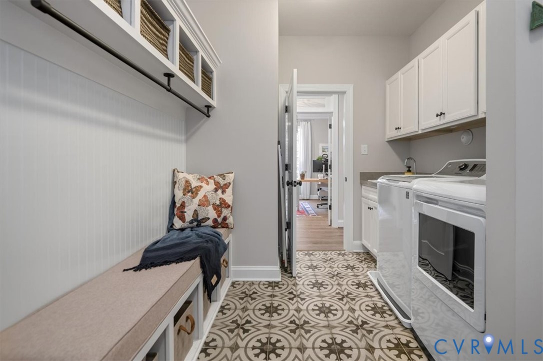 Utility room featuring patterned tile flooring, built-in cabinetry with white shaker-style doors, overhead storage cubbies, and a dedicated bench with lower storage compartments