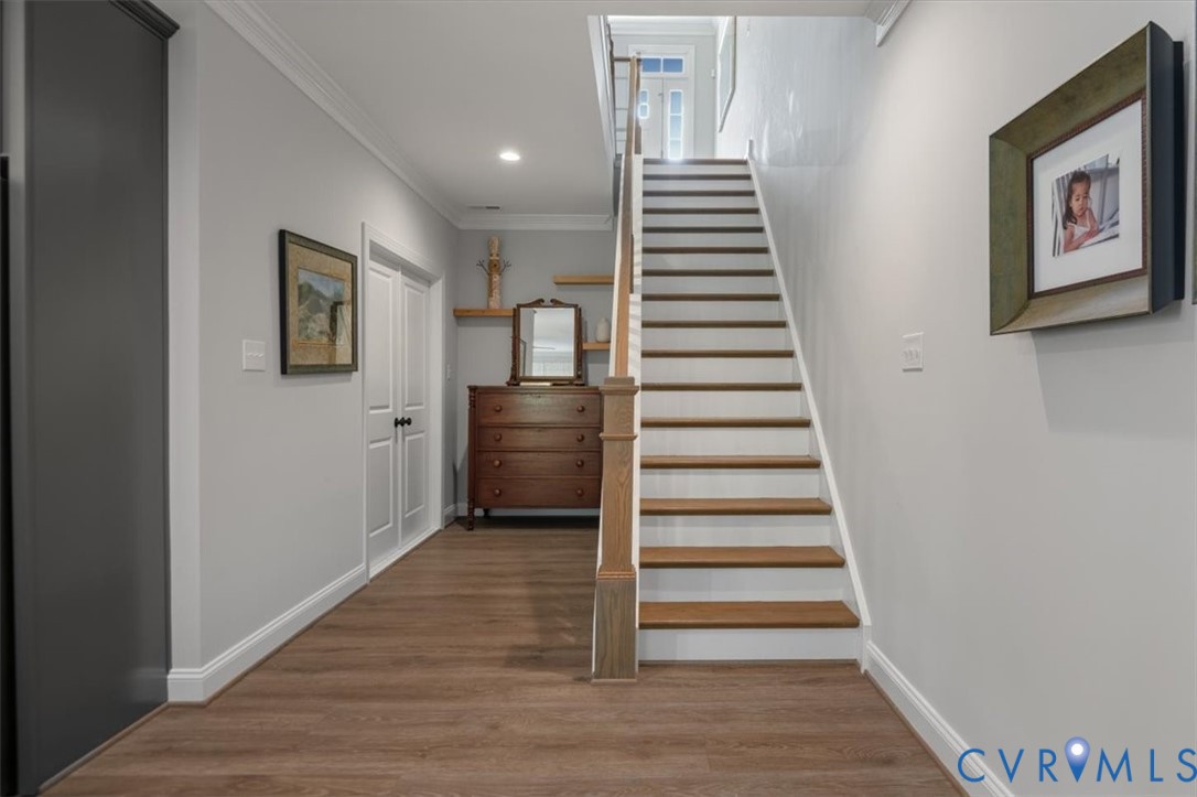 Terrace Level Foyer featuring wood-finish flooring, staircase with wood treads and white risers, decorative crown molding, and double panel interior doors