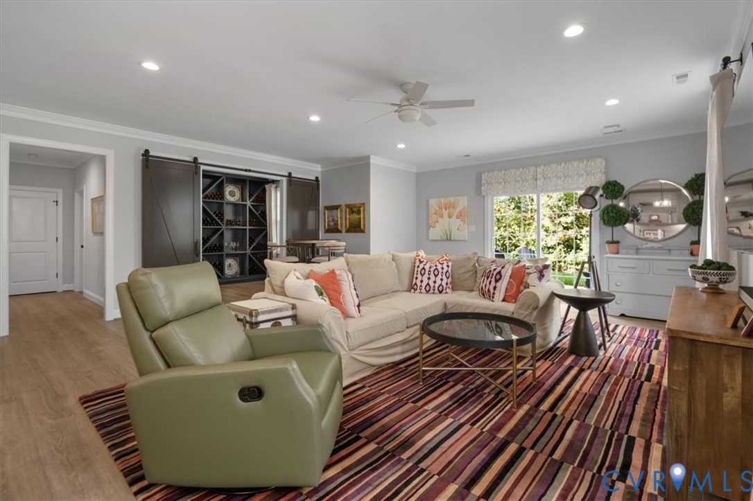 Terrace Level - Living area featuring wood-finish flooring, recessed lighting, ceiling fan, sliding glass door, and built-in shelving with sliding barn-style doors
