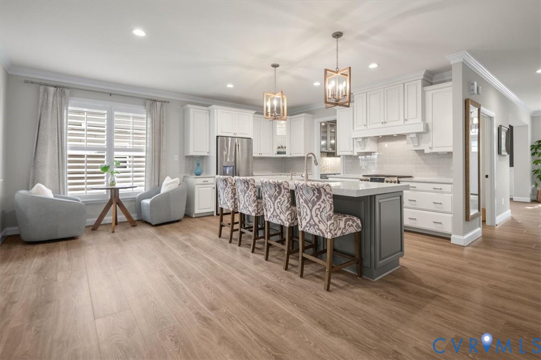 Kitchen featuring white cabinetry, quartz countertops, a grey central island, wood-finish flooring, and dual hanging pendant lights