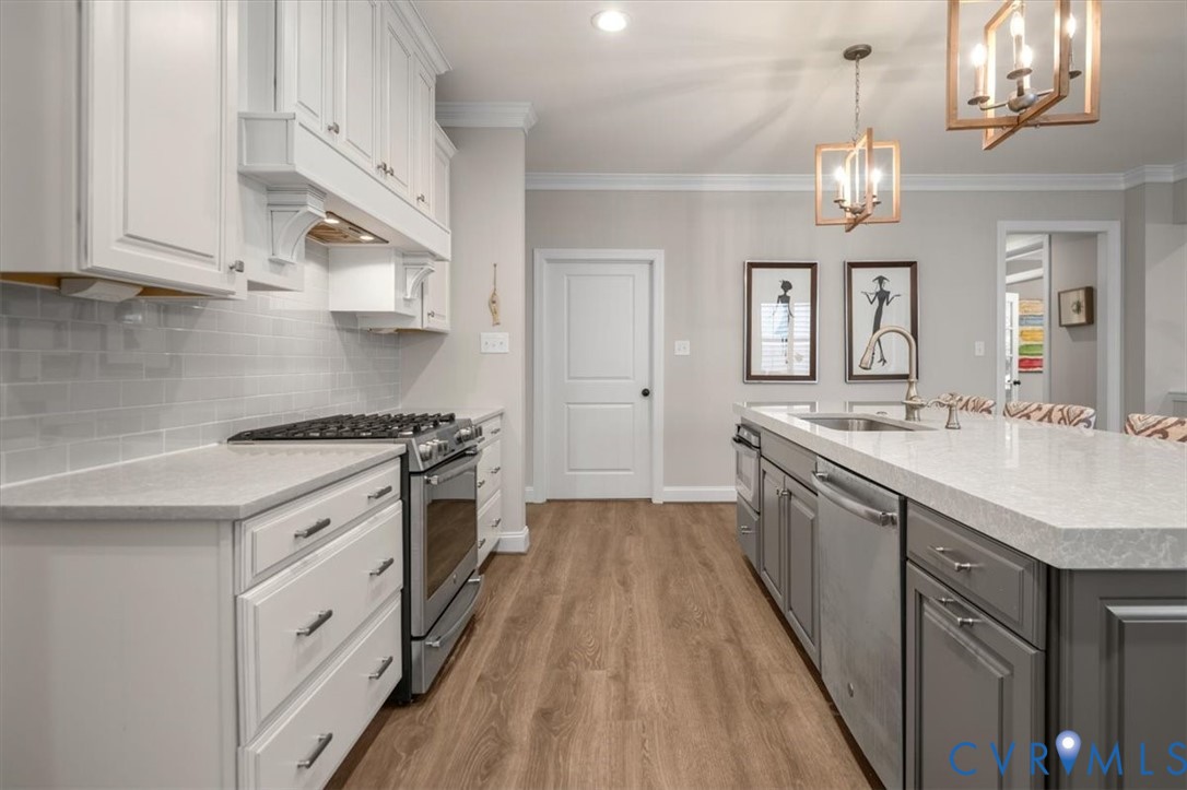 Kitchen featuring a central island with a stone-composite countertop, stainless steel appliances, shaker-style cabinetry, subway tile backsplash, and wood-finish flooring