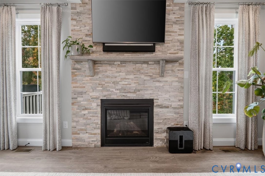 Floor-to-ceiling stacked stone fireplace featuring a substantial stone mantel and double-hung windows with exterior casing
