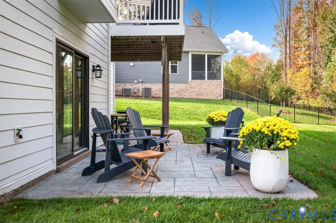 Terrace Level Stamped concrete patio featuring horizontal lap siding, a covered upper-level deck, and a black metal perimeter fence
