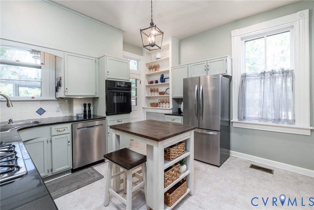 Stainless appliances, including a new refrigerator (2026), plus open shelving and windows on 2 sides.