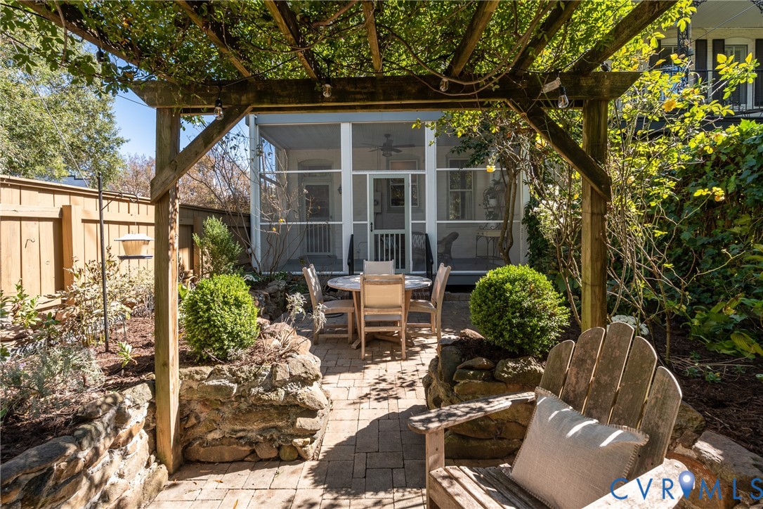 Seating under the pergola, with the screened porch beyond.