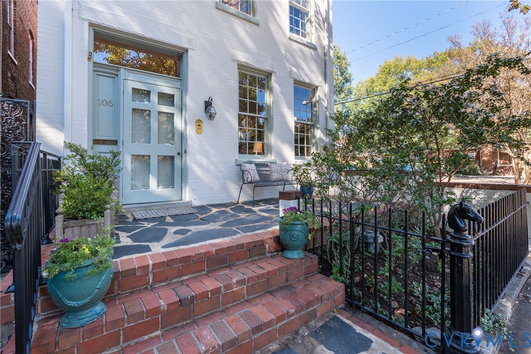 Brick steps to the flagstone porch, repointed in 2026, with new iron railings.