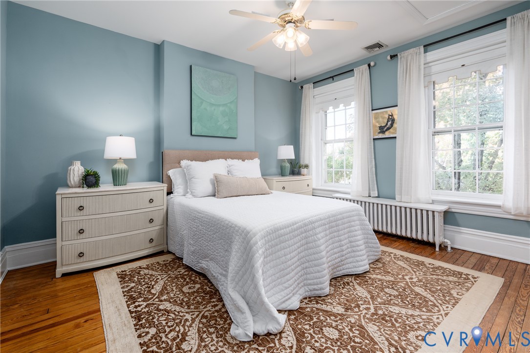 Primary bedroom with 3 front windows and hardwood floors.