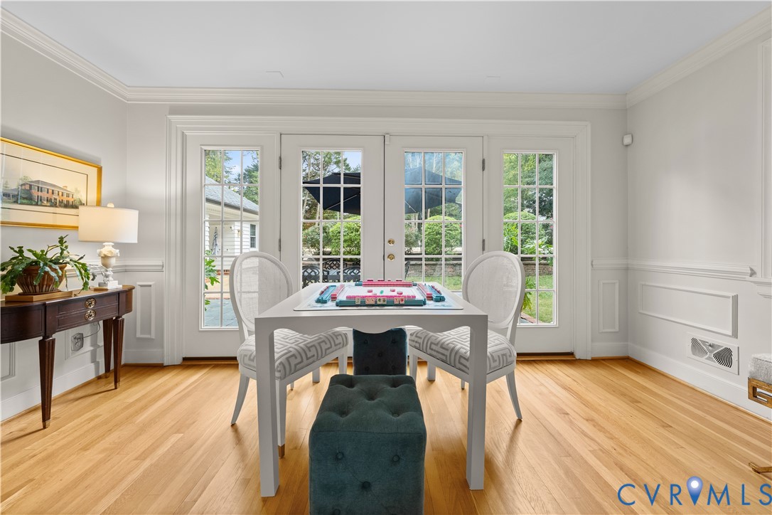 Hardwood flooring, double French doors with glass panes, crown molding, and wainscoting