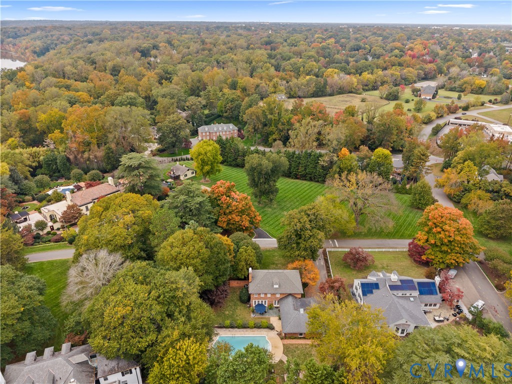 Aerial perspective featuring dense mature tree coverage, expansive green lawns, and established residential landscaping