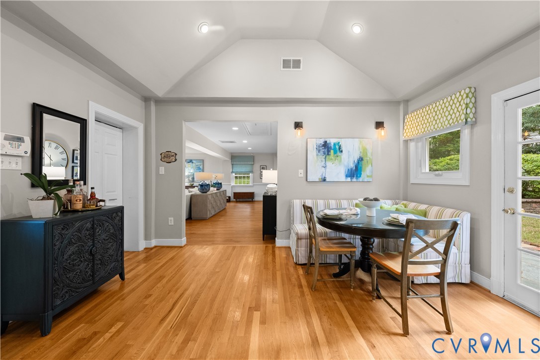 Vaulted ceiling, wood-finish flooring, recessed lighting, wall-mounted light fixtures, and multi-lite glass panel door