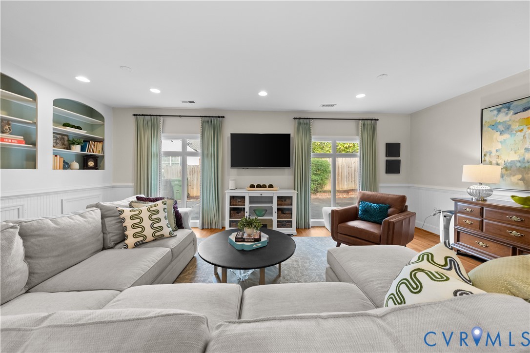 Living area featuring recessed lighting, custom built-in arched shelving, wainscoting, and dual glass-paned doors with exterior access