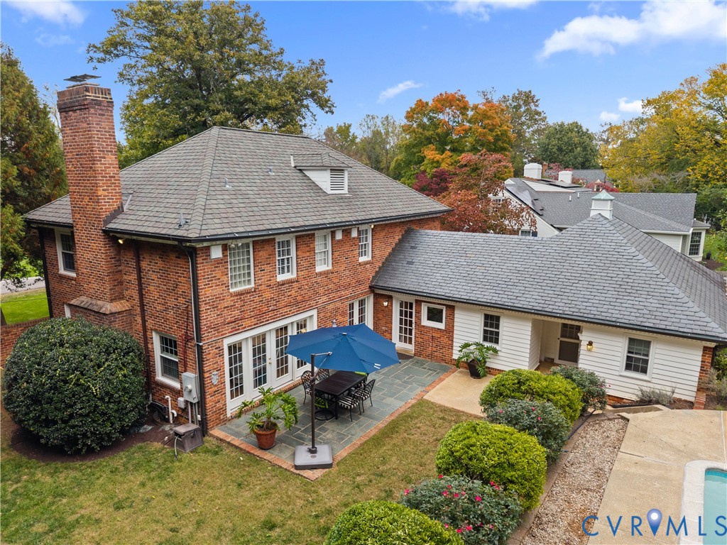 Brick exterior featuring a multi-gabled roof, exterior masonry chimney, flagstone patio, and white horizontal siding